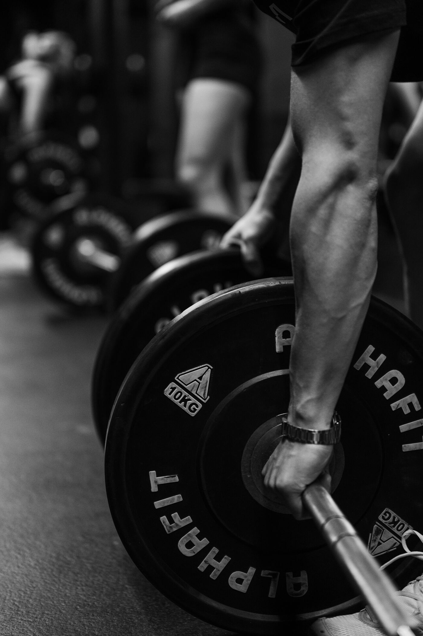 A loaded barbell on the floor as a lifter takes their grip
