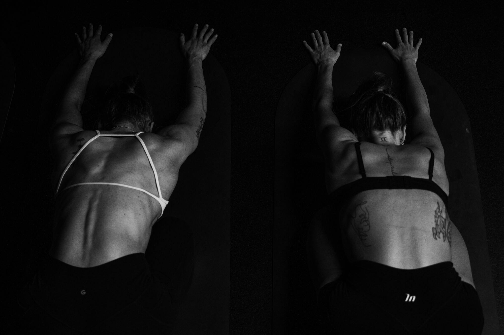 Two class members face down on their mats in the heated studio, shot from above
